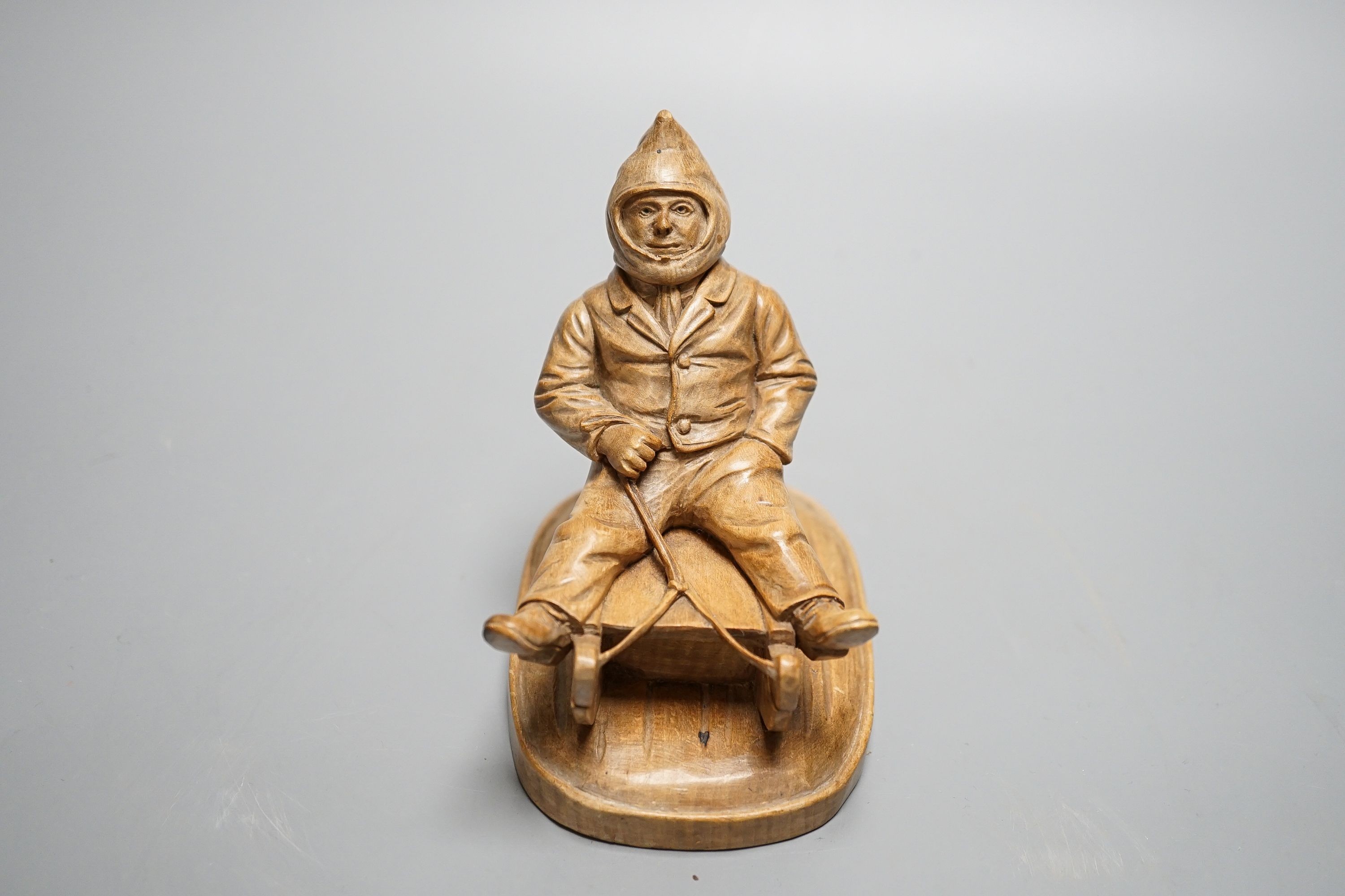 A North European novelty carved beech inkwell in the form of a seated figure sledging, c.1900, 11cm high, 11cm long.